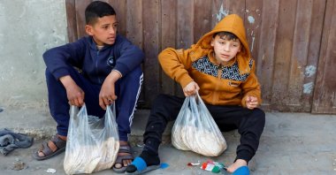 Palestinian boys rest after receiving bread from a bakery, in Rafah, in the southern Gaza Strip, Palestine, March 13, 2025. (Reuters Photo)