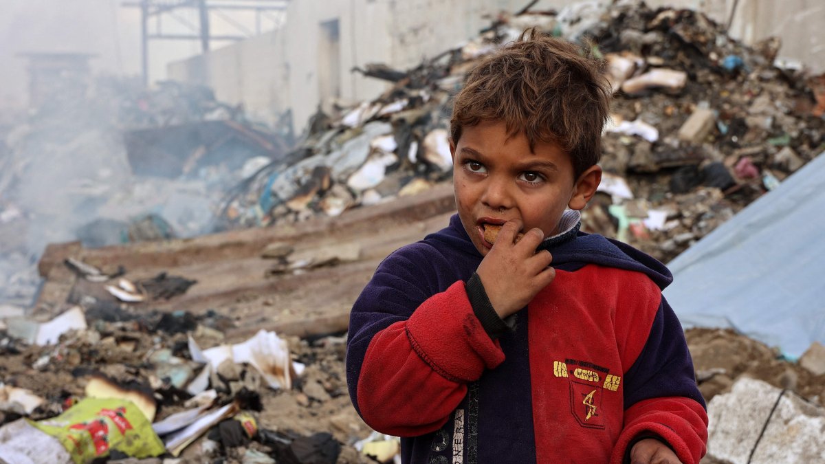 A boy looks on as he eats at a camp sheltering displaced Palestinians set up at a landfill in the Yarmuk area, Gaza City, Palestine, March 20, 2025. (AFP Photo)