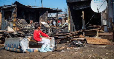 A child sits at a burnt house destroyed in a night fire in a roma settlement in Velky Saris, near Presov, Slovakia, March 20, 2025. (AFP Photo)
