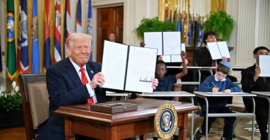 U.S. President Donald Trump holds an executive order after signing it alongside U.S. Secretary of Education Linda McMahon (R) in the East Room of the White House, Washington, U.S., March 20, 2025. (AFP Photo)