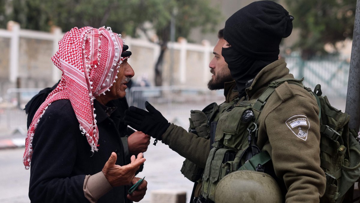 A Palestinian Muslim man heading to the Al-Aqsa Mosque Complex talks with an Israeli border guard as he crosses a checkpoint, Bethlehem, West Bank, Palestine, March 21, 2025. (AFP Photo)