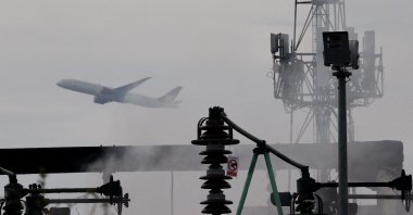 A plane takes off, as smoke rises from an area of an electrical substation a day after it caught fire and wiped out power at Heathrow International Airport, near London, Britain, March 22, 2025. (Reuters Photo)