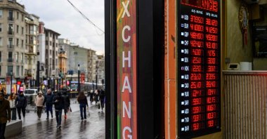 People walk past a currency exchange board in Istanbul, Türkiye, March 20, 2025. (AFP Photo)