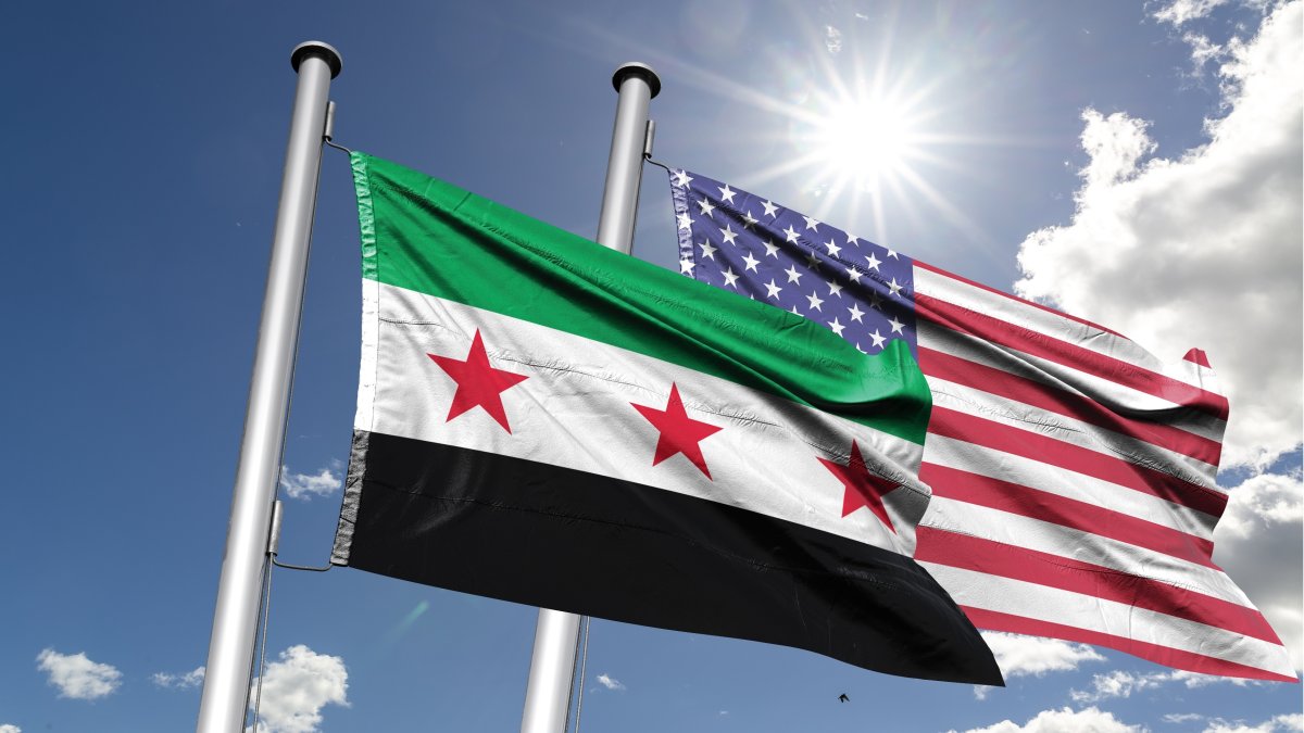 The Syrian (L) and the U.S. flags fly under the sun. (Shutterstock Photo)