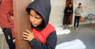 A child stands near the bodies of Palestinians killed in Israeli strikes, at Al-Ahli Arab Baptist hospital, in Gaza City, central Gaza, Palestine, March 26, 2025. (Reuters Photo)