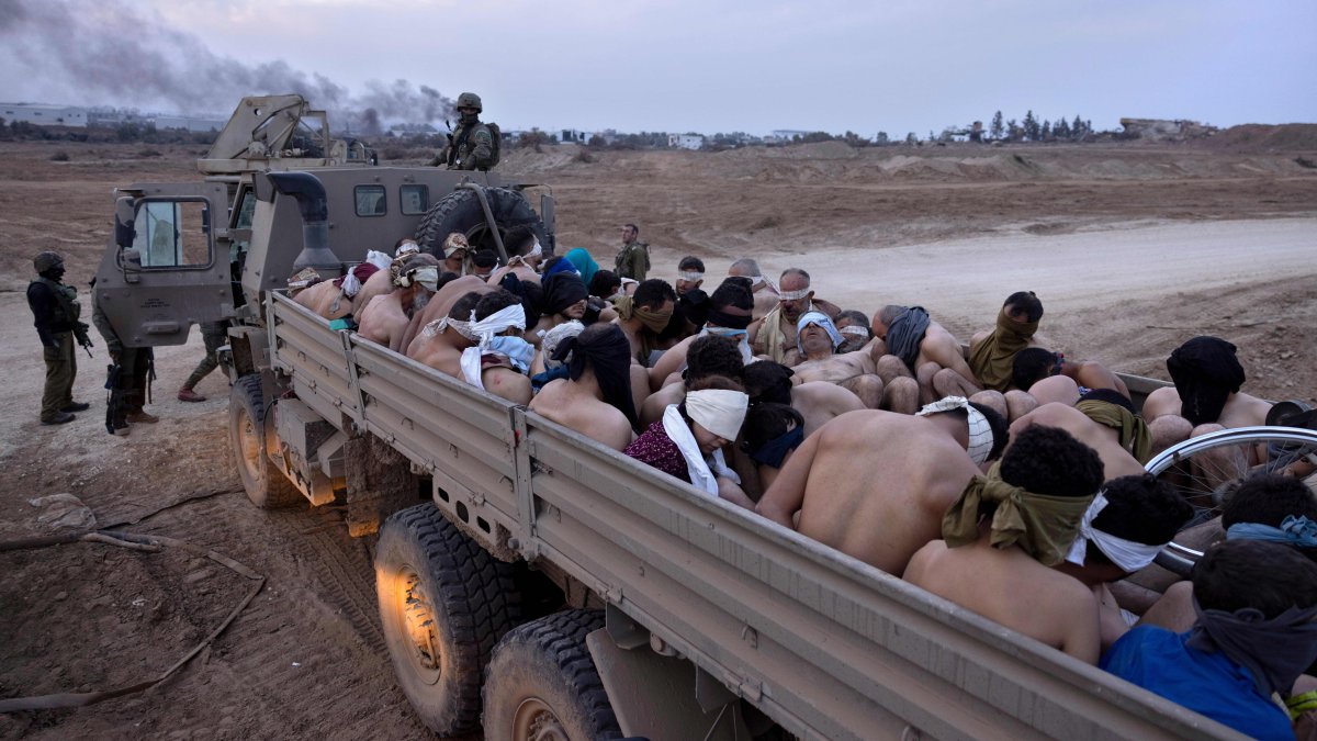 Israeli soldiers stand by a truck packed with bound and blindfolded Palestinian detainees, Gaza Strip, Palestine, Dec. 8, 2023. (AP Photo)
