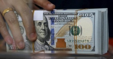 An employee of a money changer holds a stack of U.S. dollar notes before giving it to a customer, Jakarta, Indonesia, Oct. 8, 2015. (Reuters Photo)