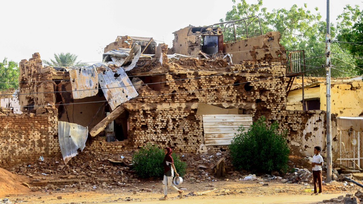 A Sudanese boy looks on as a woman walks past a damaged building in Khartoum's twin city Omdurman, Sudan, March 20, 2025. (AFP Photo)
