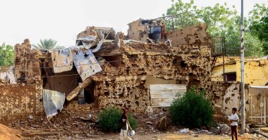 A Sudanese boy looks on as a woman walks past a damaged building in Khartoum's twin city Omdurman, Sudan, March 20, 2025. (AFP Photo)