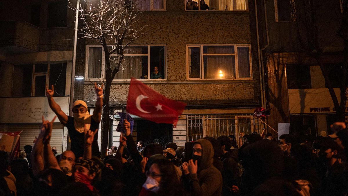 Residents of an apartment building look out as students march along a street during a rally in support of the Istanbul mayor's arrest, Istanbul, Türkiye, March 25, 2025. (AFP Photo)