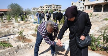 A man tries to fix a tomb as people visit their dead relatives at the destroyed Yarmouk camp cemetery, during the Eid al-Fitr, Damascus, Syria, March 31, 2025. (EPA Photo)