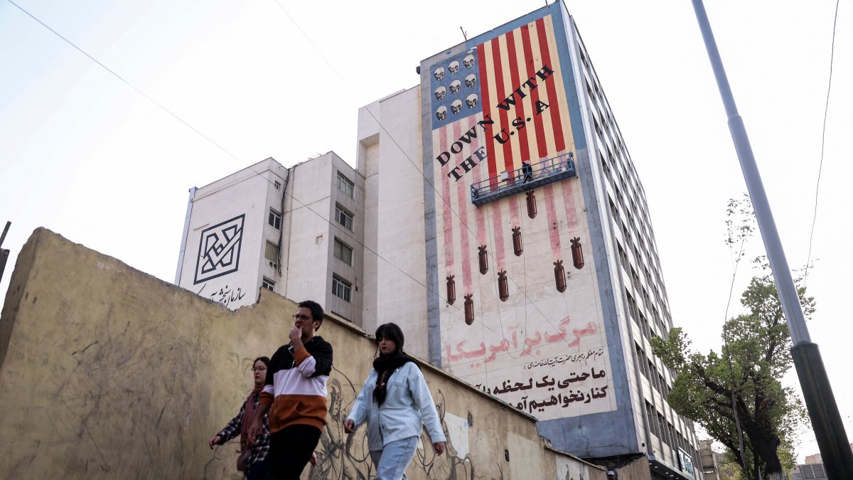 People walk by as a painter repaints an anti-U.S. mural, Tehran, Iran, March 29, 2025. (Reuters Photo)