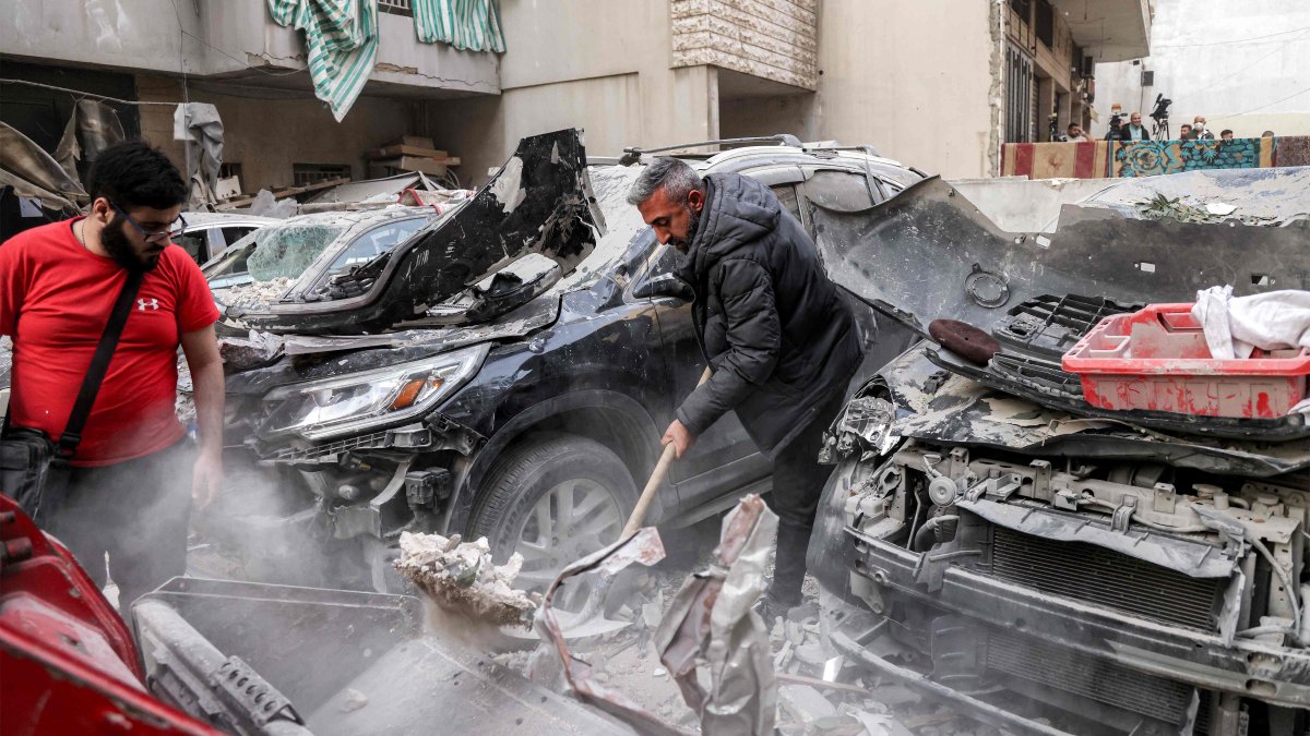 A man clears debris with a shovel by heavily damaged vehicles at the site of an Israeli strike in Beirut's southern suburbs, Lebanon, April 1, 2025. (AFP Photo)