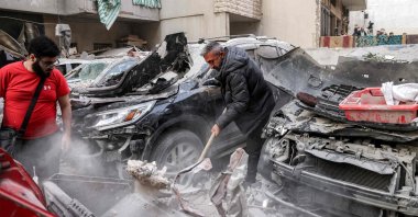 A man clears debris with a shovel by heavily damaged vehicles at the site of an Israeli strike in Beirut's southern suburbs, Lebanon, April 1, 2025. (AFP Photo)