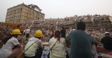 Family members of earthquake victims watch the rescue operation as they sit near the collapsed Sky Villa in Mandalay, Myanmar, March 31, 2025. (EPA Photo)