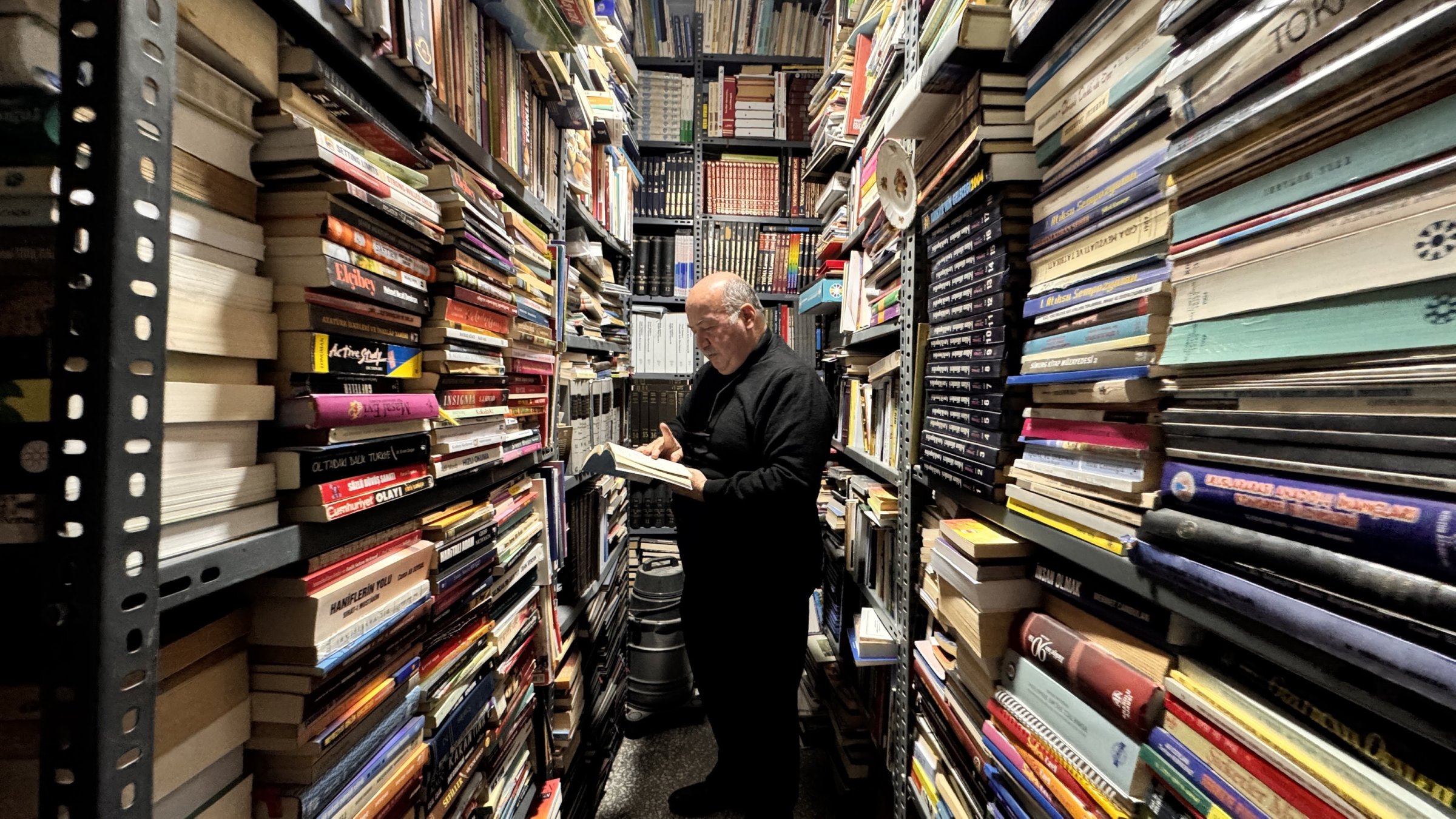 Faruk Yaman stands among his vast book collection in his home-turned-library, Kayseri, central Türkiye, March 31, 2025. (AA Photo)