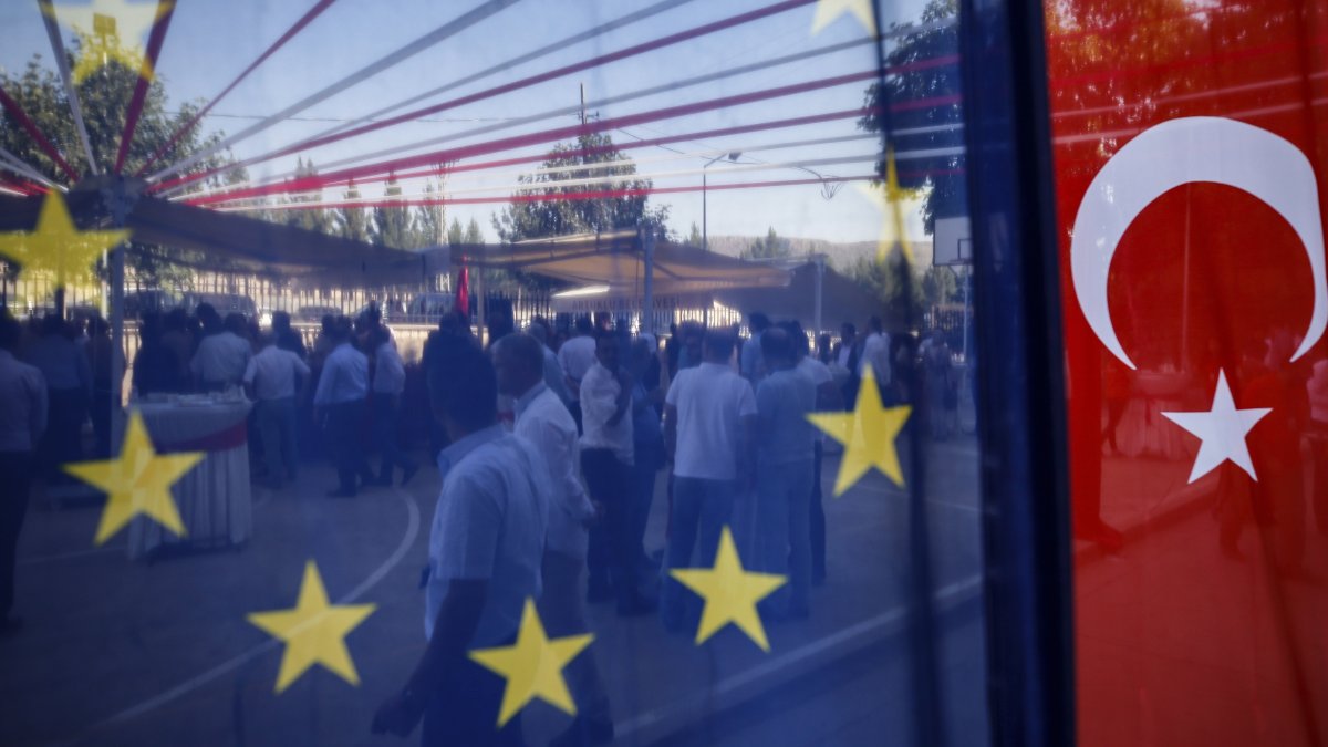 People are seen behind a European Union and a Turkish flag, as they attend an event in Mardin, southern Türkiye, July 11, 2018. (AP Photo)