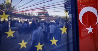 People are seen behind a European Union and a Turkish flag, as they attend an event in Mardin, southern Türkiye, July 11, 2018. (AP Photo)