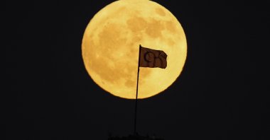 A Turkish flag is silhouetted against a full moon as it rises behind old Karahisar castle in Afyonkarahisar, central Türkiye, June 21, 2024. (AP Photo)