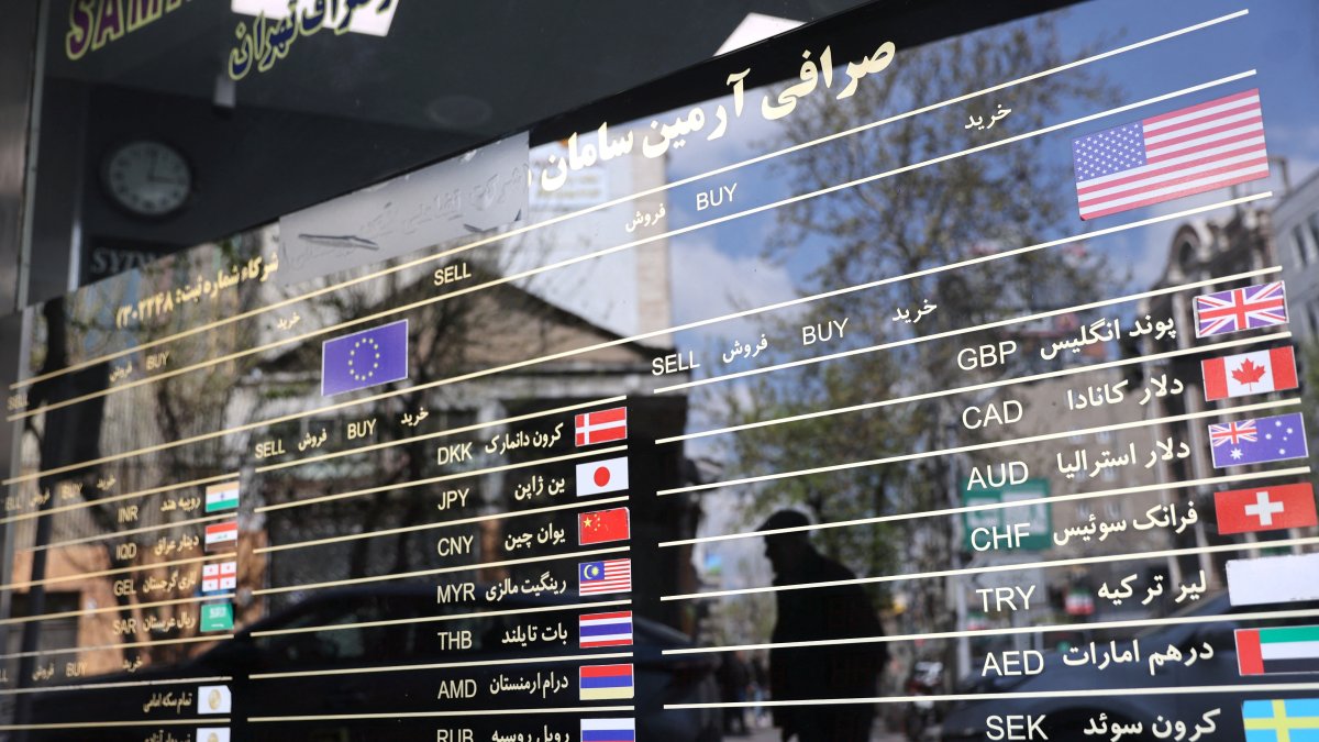 The American, EU and other flags are seen on a signboard at a currency exchange as the value of the Iranian rial drops, Tehran, Iran, March 26, 2025. (Reuters Photo)
