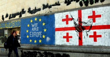 A woman walks past a mural of flags of Georgia and the European Union, central Tbilisi, Georgia, March 6, 2025. (AFP Photo)