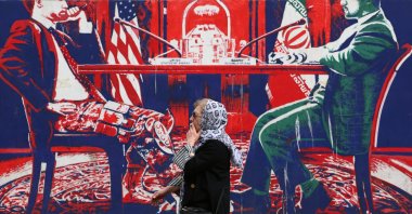 An Iranian woman smokes as she walks next to an anti-U.S. mural, next to the former U.S. Embassy, Tehran, Iran, April 7, 2025. (EPA Photo)