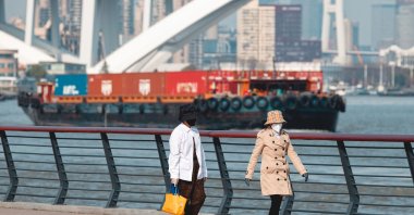 People walk on the riverbank while cargo ships sail on the Huangpu River, Shanghai, China, April 3, 2025. (EPA Photo)
