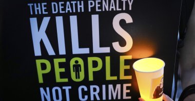 An activist holds a candle and a placard during a vigil against the impending execution of Malaysian national Pannir Selvam Pranthaman, sentenced to death for trafficking heroin into Singapore, in Kuala Lumpur, Malaysia, Feb. 19, 2025. (AP Photo)