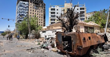 Members of army walks near a destroyed military vehicle and bombed buildings, as Sudan's army retakes ground and some displaced residents return to ravaged capital in the state of Khartoum, Sudan, March 26, 2025. (Reuters Photo)