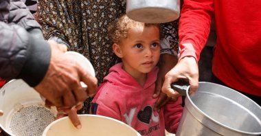 A child looks on as Palestinians wait to receive food cooked by a charity kitchen, in Khan Younis, southern Gaza Strip, Palestine, April 6, 2025. (Reuters Photo)