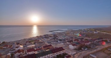A sunset view over the Caspian Sea with Aktau&#039;s cityscape stretching along the shoreline, Kazakhstan. (Shutterstock Photo)