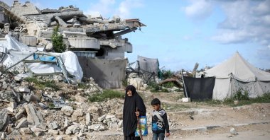 A displaced Palestinian woman and child walk past the rubble of a destroyed building in the Gaza Strip, Palestine, April 10, 2025. (AFP Photo)
