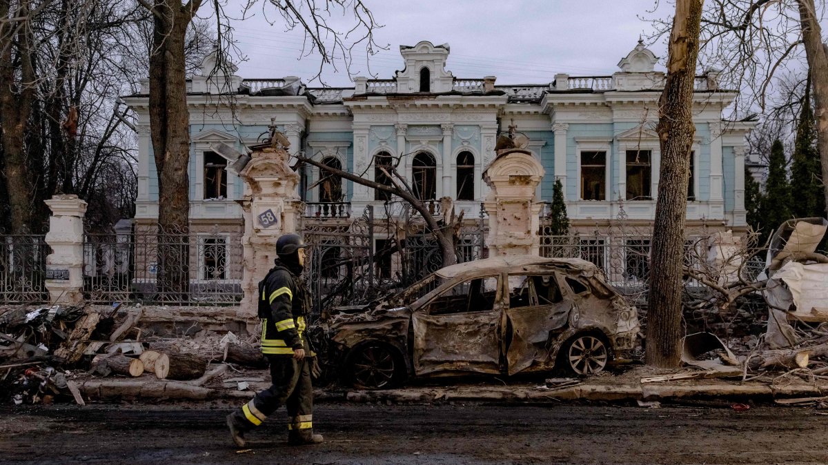 A Ukrainian rescuer walks by a burned car in front of a damaged building at the site of a missile attack in Sumy, northeastern Ukraine, April 13, 2025. (AFP Photo)