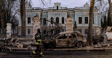 A Ukrainian rescuer walks by a burned car in front of a damaged building at the site of a missile attack in Sumy, northeastern Ukraine, April 13, 2025. (AFP Photo)