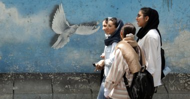 A group of Iranian women walks next to a peace bird wall painting in a street in Tehran, Iran, April 13, 2025. (EPA Photo)