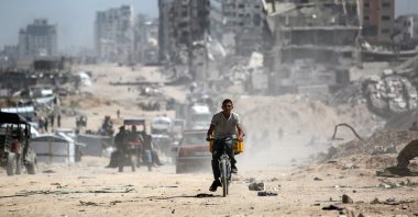 A youth rides a bicycle as people commute along the al-Rashid road, the only route linking the northern and southern parts of the Palestinian territory, Apr. 2, 2025. (AFP Photo)