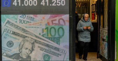 A woman walks past a currency exchange board, Istanbul, Türkiye, March 20, 2025. (AFP Photo)