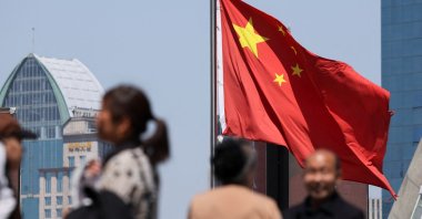 A Chinese national flag flies as people walk on a pedestrian bridge at the Lujiazui financial district, Shanghai, China, April 15, 2025. (Reuters Photo)