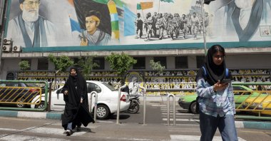 Iranians walk next to a huge wall painting of Iranian supreme leader Ayatollah Ali Khamenei (Top-R) and late supreme leader Ayatollah Ruhollah Khomeini (Top-L) in a street, in Tehran, Iran, April 13, 2025. (EPA Photo)
