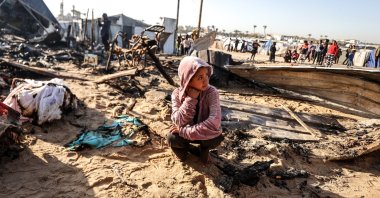 A Palestinian girl sits amid burned-out tents after an Israeli airstrike in Khan Younis, southern Gaza, Palestine, April 17, 2025. (AA Photo)