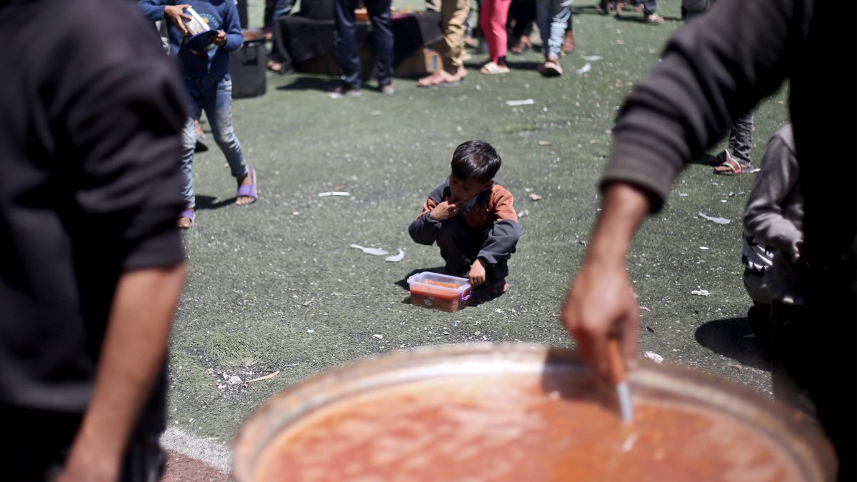 A Palestinian child eats his portion of a hot meal at a free food distribution point at the Nuseirat refugee camp in the central Gaza Strip, Palestine,  April 19, 2025. (AFP Photo)