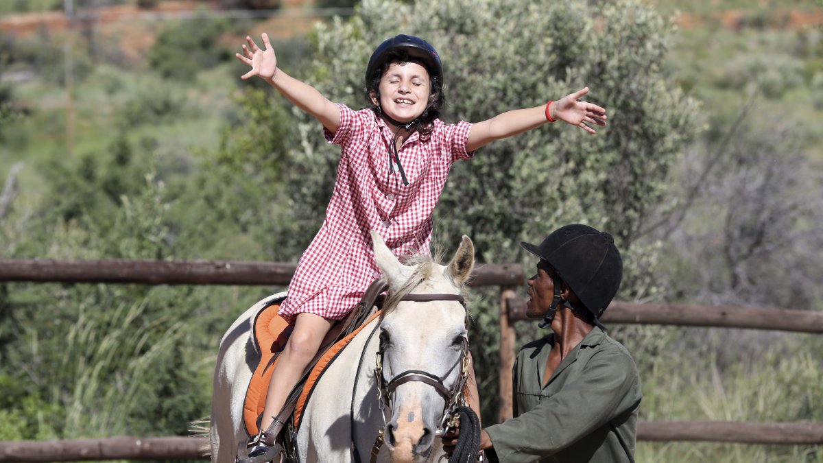 Immanuel Hoxobeb assists Alicia who participates in the "Enabling Through the Horse," therapy program outside Windhoek, Namibia, Feb. 18, 2025. (AP Photo)