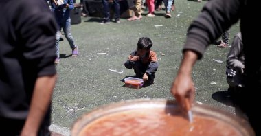 A Palestinian child eats his portion of a hot meal at a free food distribution point at the Nuseirat refugee camp in the central Gaza Strip, Palestine,  April 19, 2025. (AFP Photo)