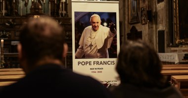 People sit in front of the portrait and floral tribute to Pope Francis placed to mourn his death at the Santa Maria Church, in Istanbul, Türkiye, April 21, 2025. (EPA Photo)