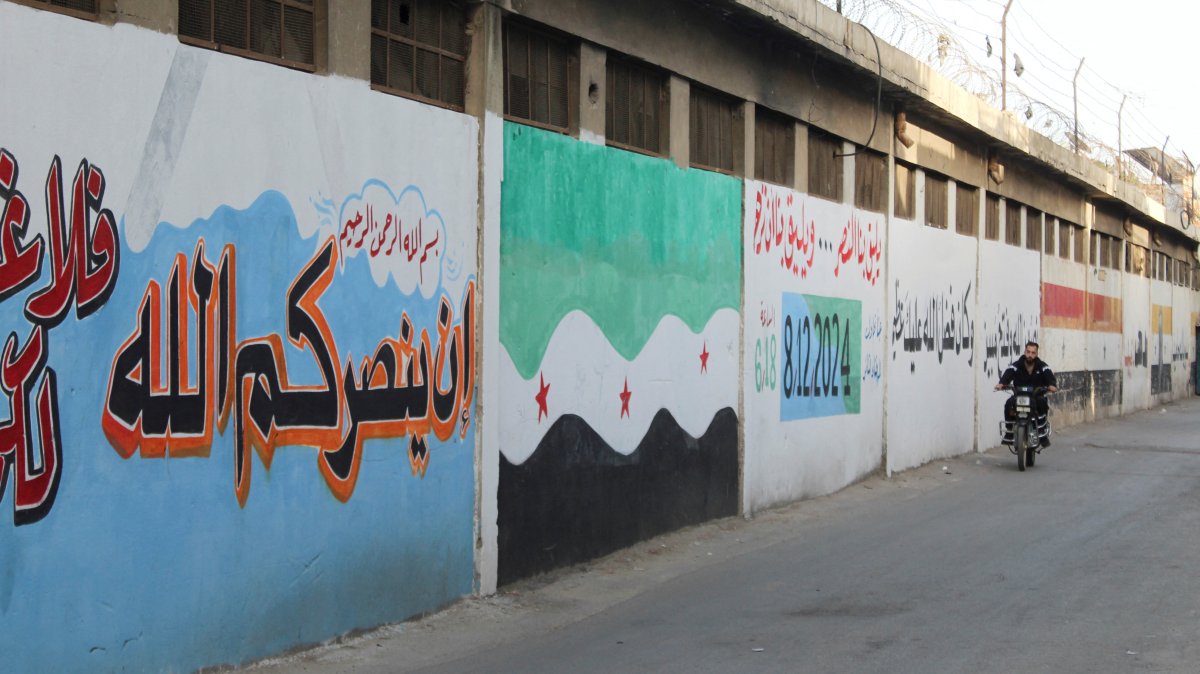 A man riding a motorcycle passes next to a wall painted in the colors of the new Syrian flag in al-Qadam neighbourhood in Damascus, Syria, March 26, 2025. (Reuters Photo)