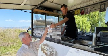 A local shopkeeper distributes traditional lokma to a resident in memory of Pope Francis following his death, in Iznik, Bursa, northwestern Türkiye, April 21, 2025. (IHA Photo)