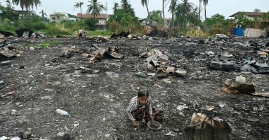 A woman searches for items among the debris of houses destroyed in an earthquake-sparked fire in Mandalay, April 11, 2025. (AFP Photo)