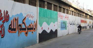 A man riding a motorcycle passes next to a wall painted in the colors of the new Syrian flag in al-Qadam neighbourhood in Damascus, Syria, March 26, 2025. (Reuters Photo)