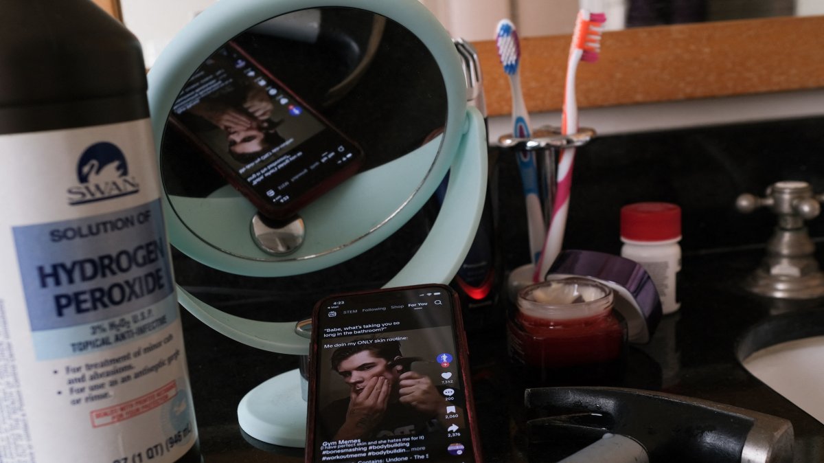 An illustration photo shows a video of a TikTok influencer hammering his cheekbone, playing on a smartphone in a bathroom next to a bottle of hydrogen peroxide and a hammer, Los Angeles, U.S., April 11, 2025. (AFP Photo)