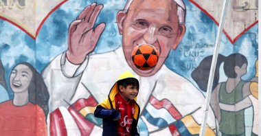 A child plays in front of a Pope Francis mural at the Iglesia of 'Cristo Obrero' football field, Buenos Aires, Argentina, April 14, 2024. (Getty Images Photo)